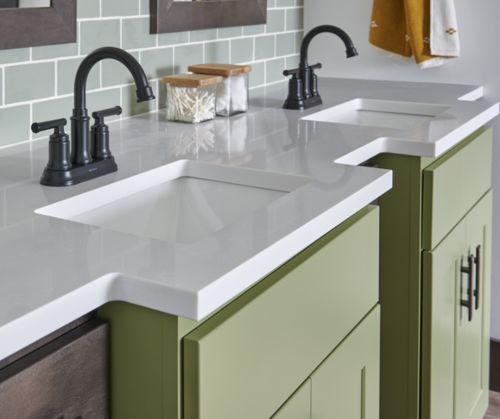A white bathroom countertop atop of green cabinets