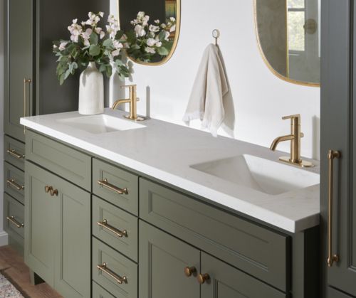 A beautiful bathroom vanity with green cabinets and white countertops