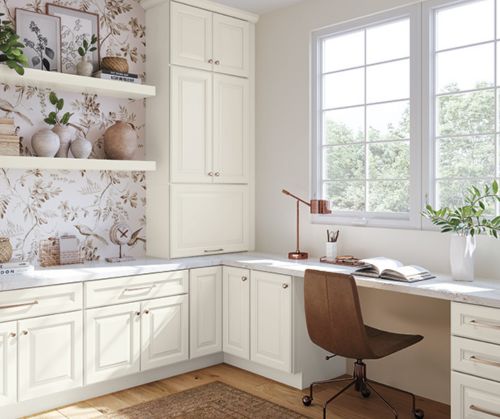 A cozy home office with cream cabinets and light shining through the window